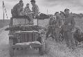 Commandos look on German prisoners are taken away by Jeep on the 7th June. IWM B5203.