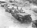 A jeep and trailer of the 9th Infantry Battalion, loaded with stores, ploughing through the mud and slush of the Mosigetta Road