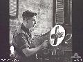 BALIKPAPAN, BORNEO. 1945-09-04. PRIVATE W. D. SEALEY PAINTING A RED CROSS SIGN ON THE CANOPY OF AN AMBULANCE JEEP OF 10TH FIELD AMBULANCE.