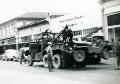 US servicemen monitor a truck towing a jeep on a city street. Aberdeen, Washington. 1942